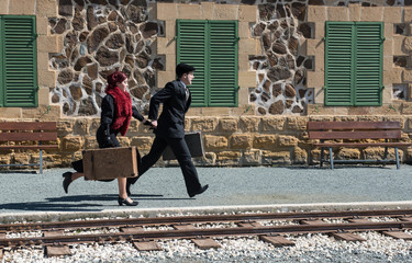 Young couple with vintage suitcase on the trainlines ready for a journey.