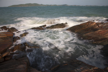 The waves breaking on a stony beach, forming a spray in Thailand