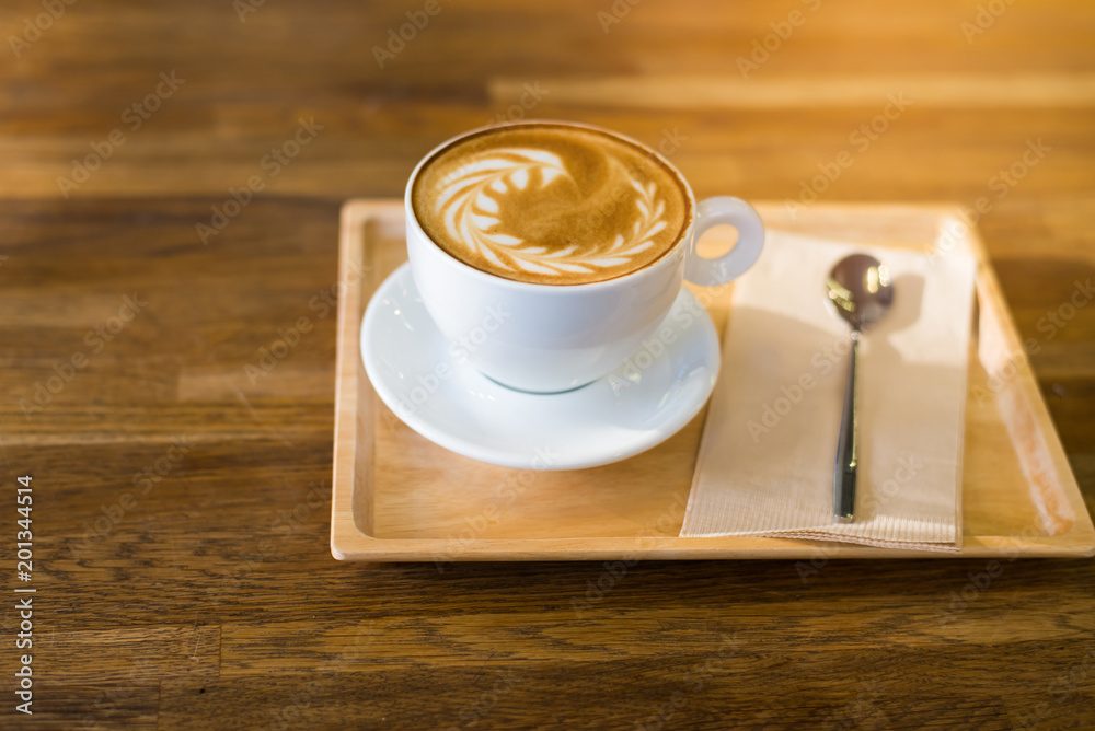 Wall mural a cup of hot latte art coffee on wooden table