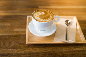 A Cup of hot latte art coffee on wooden table