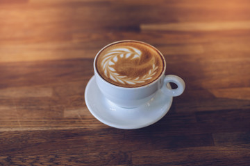 A Cup of hot latte art coffee on wooden table