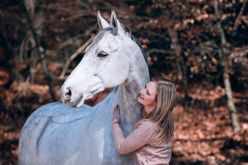 Reiterin kuschelt mit ihrem Pferd im Herbst ohne alles