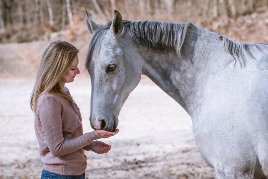Frau schmust mit ihrem wei&szlig;en Pferd im Winter