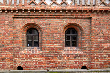 Fototapeta na wymiar Red brick wall of an old house with windows.