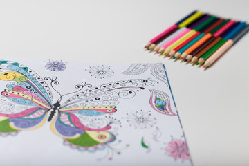 many colored pencils and coloring book on the white table