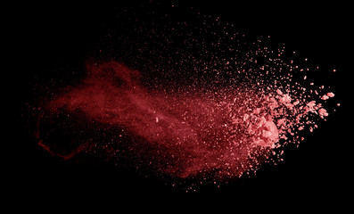 Abstract colored red powder explosion isolated on black background.