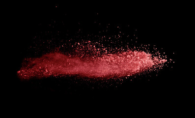 Abstract colored red powder explosion isolated on black background.