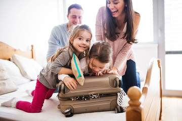 Young family with two children packing for holiday. - obrazy, fototapety, plakaty