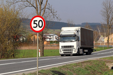Limiting the speed of traffic to 50 km/h. Road sign on the highway. safety of traffic. Motor transportation of passengers and cargoes. Modern cars. A large truck is moving along the road.