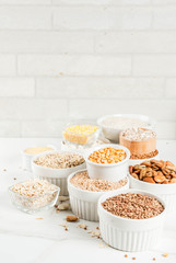 Selection various types cereal grains groats  in different bowl on white marble background,  space for text