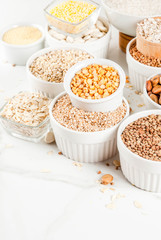 Selection various types cereal grains groats  in different bowl on white marble background, copy space