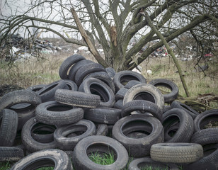 Tyres dumped around damaged tree in illegal waste dump, West Midlands, UK