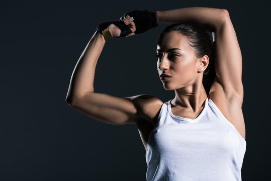 strong sportswoman showing muscular biceps, isolated on grey