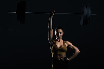 attractive strong bodybuilder holding barbell, isolated on black
