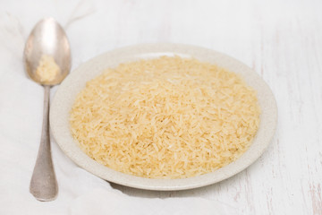uncooked rice on plate on wooden background