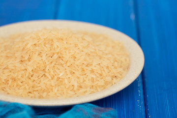 uncooked rice on plate on wooden background