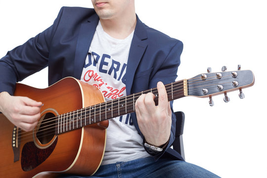 Closeup of a guy is learning to play an acoustic guitar.