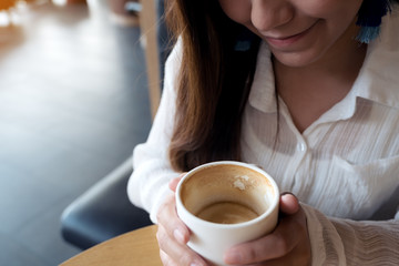 Closeup image of an Asian woman holding a coffee cup before drinking with feeling good in cafe