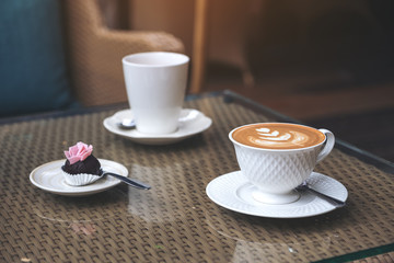 A piece of snack and two white coffee cups on table in cafe