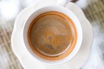 Top view image of a cup of hot black coffee on table