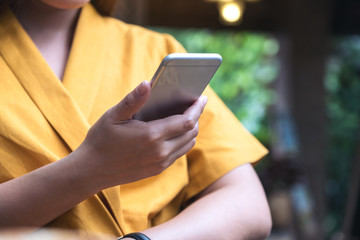 Closeup image of a woman holding , using and looking at smart phone