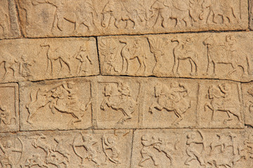 Stone bas-reliefs on the walls in Temples Hampi. Carving stone ancient background. Carved figures made of stone. Unesco World Heritage Site. Karnataka, India. Beige background.