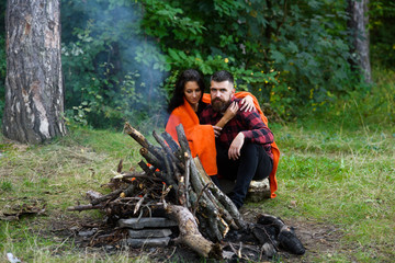 Couple in love at picnic with fire in forest, trees