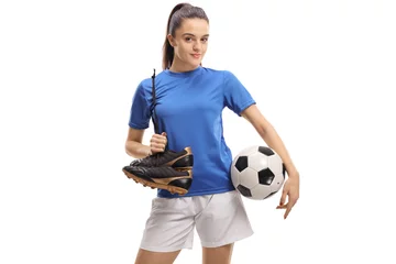 Rolgordijnen Female soccer player holding a pair of cleats and a football © Ljupco Smokovski