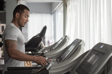 Fototapeta na wymiar Muscular builder man running in machine treadmill at fitness gym club