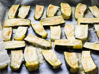 Zucchini halves baked with herbs and cheese on baking parchment
