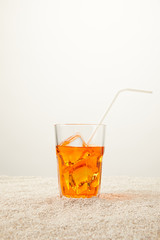 close up view of refreshing cocktail with ice and straw on sand on grey background