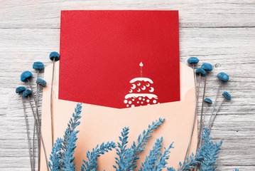 Festive postcard in an envelope and flowers on a wooden background