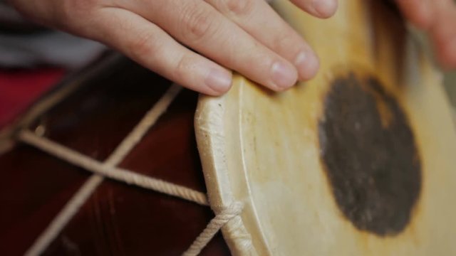 Close up of hands of a man playing a drum.