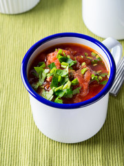 Russian beetroot soup borscht in enamel mugs on green cloth