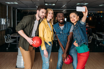 happy young friends taking selfie together at bowling club