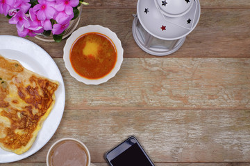 Malaysian favourites food for breakfast egg bread or Roti Telur served with lentil curry, a mug of...