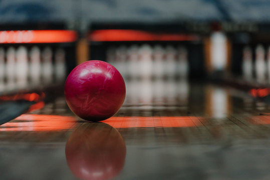close-up shot of red bowling ball lying on alley under warm light