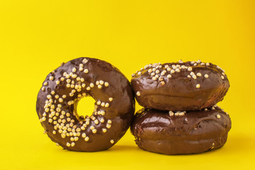 chocolate donut lies one on the other, on a yellow background