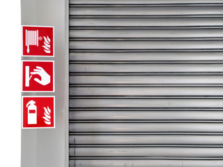 Real-use standard fire symbol labels, fire hose, fire switch, Dry Powder Fire Extinguisher, hanging in front of roll door of factory or warehouse