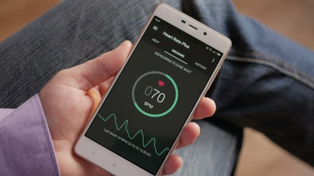 Man Looking At Health Monitoring App On Smartphone. Monitoring the heart pulse with a health application on smartphone.