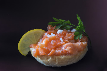 small sandwich with fillet of red salmon fish on a dark background