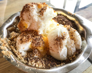Close-up vanilla ice cream with tangerine syrup, chocolate and nuts