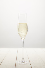 closeup view of champagne glass with bubbles on white wooden table