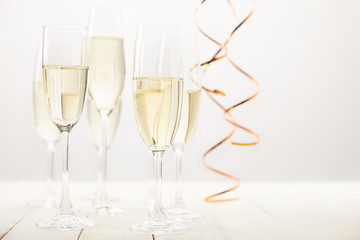 close up view of champagne glasses with ribbons on white wooden table, holiday concept