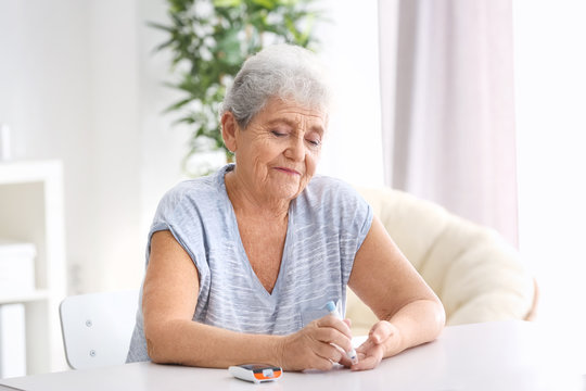 Elderly Woman With Diabetes Measuring Level Of Blood Sugar At Home