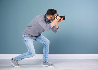 Male photographer with camera near grey wall