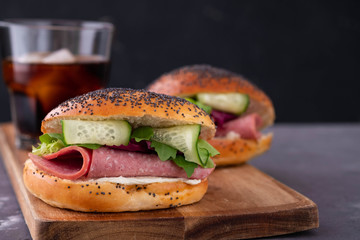 Bagels with cream, avocado, tomatos and arugula on wooden board and table background. Healthy breakfast food. Copy space
