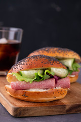 Bagels with cream, avocado, tomatos and arugula on wooden board and table background. Healthy breakfast food. Copy space