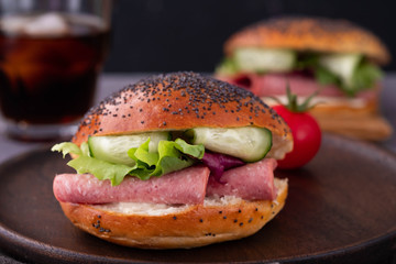 Bagels with cream, avocado, tomatos and arugula on wooden board and table background. Healthy breakfast food. Copy space