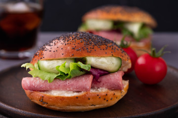 Bagels with cream, avocado, tomatos and arugula on wooden board and table background. Healthy breakfast food. Copy space